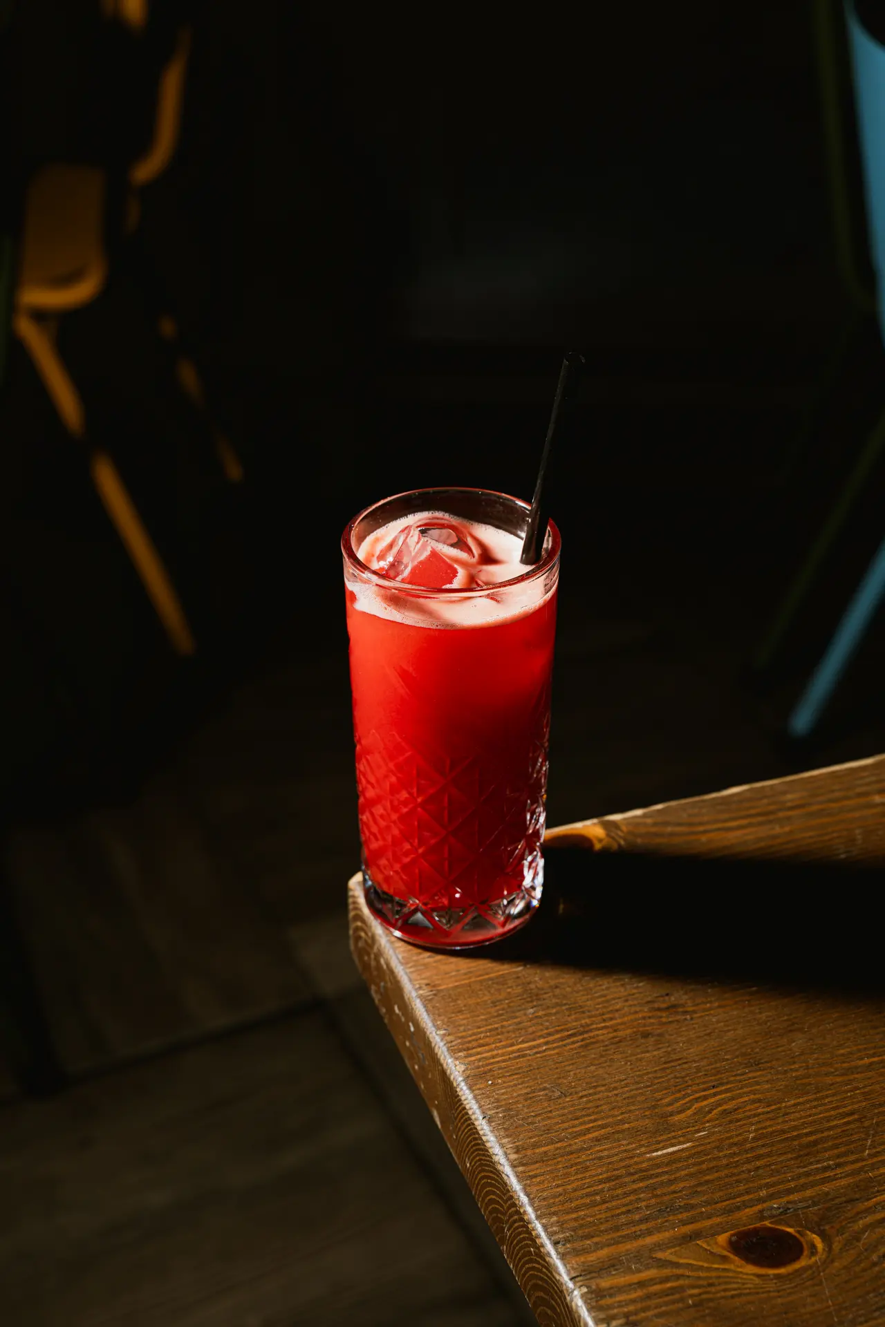 Un cocktail rosso sullo spigolo di un tavolo di legno